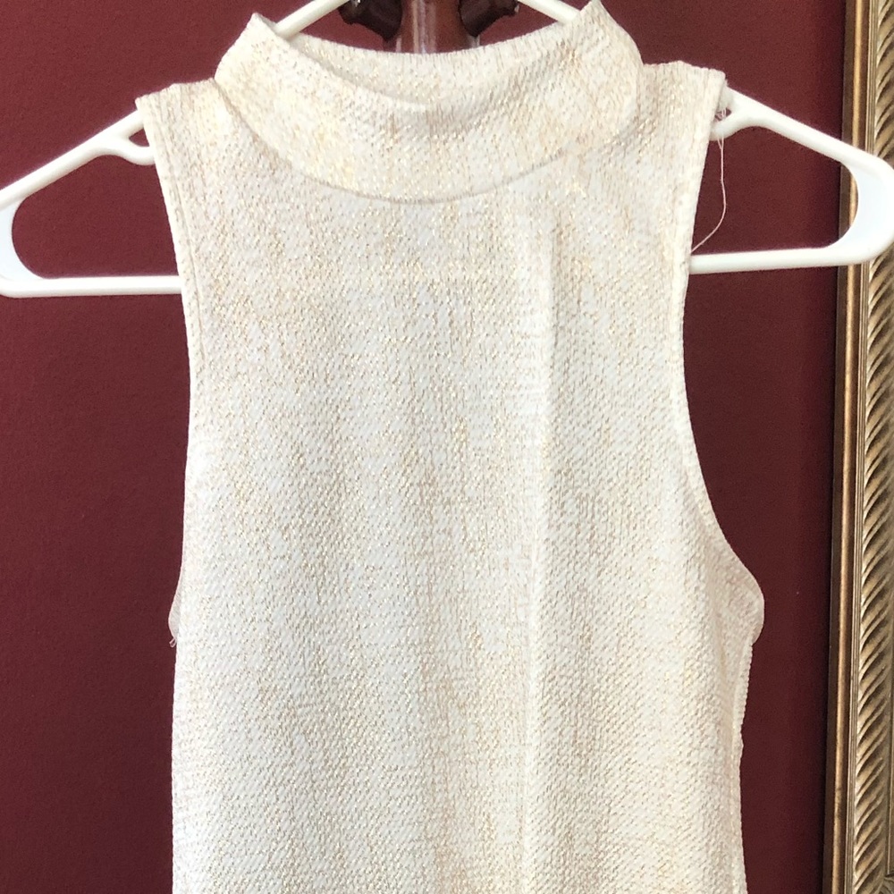White sleeveless dress with gold print.